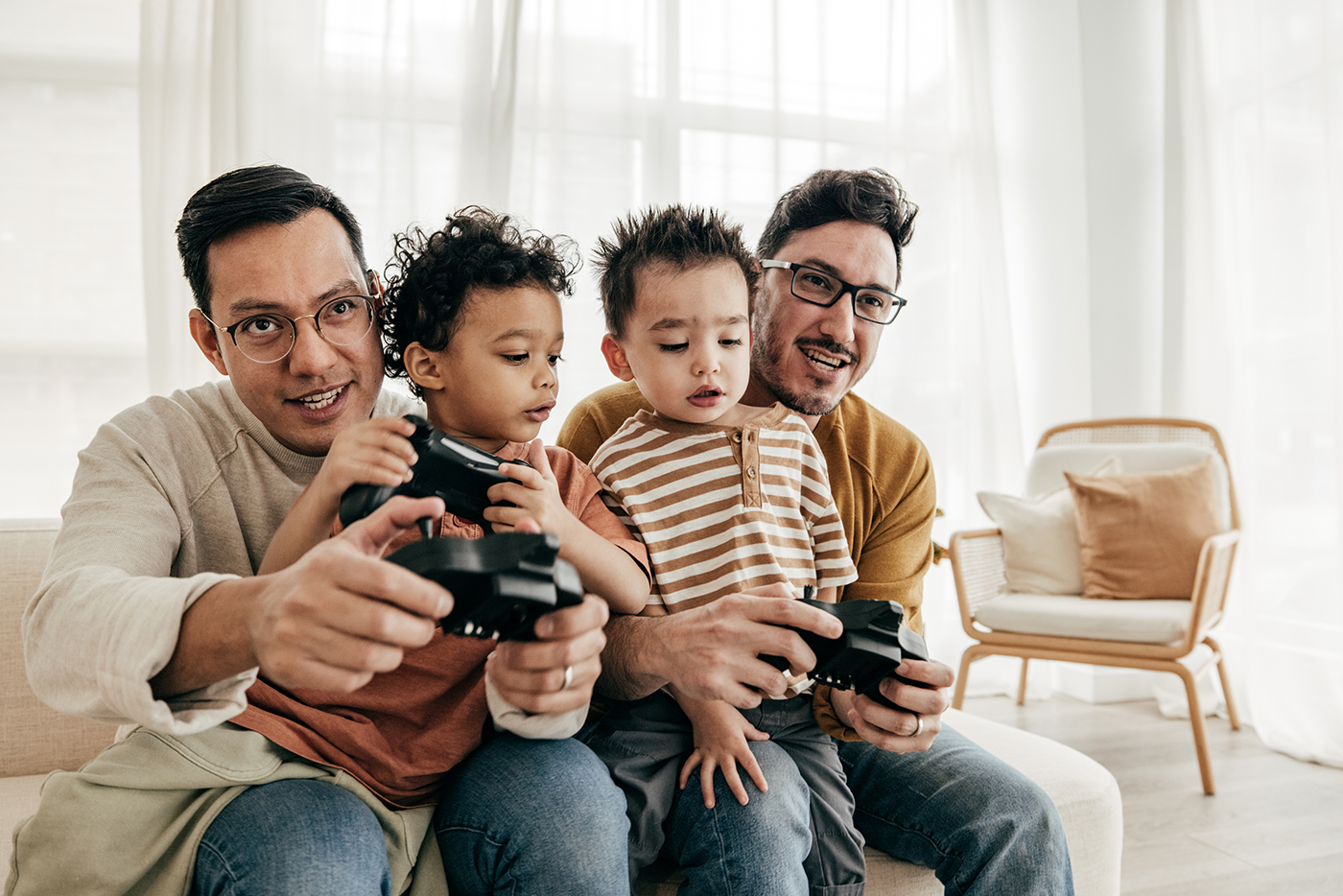 Two latino fathers with their twins play a video game