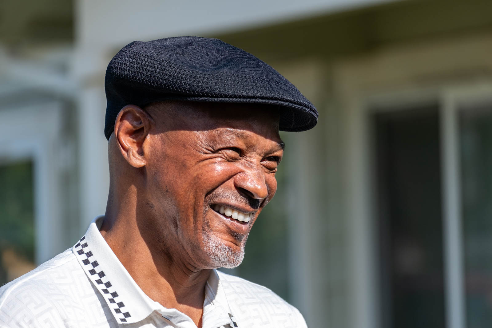 a photograph of a smiling older Black man with a hat smiling