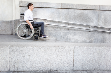 Person using a wheelchair on concrete ramp.