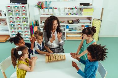 Teacher playing music and clapping hands with children.