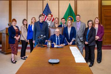 A group of people smile at the camera at a Washington State Bill signing. Legislative Director Omar Santana is pictured.