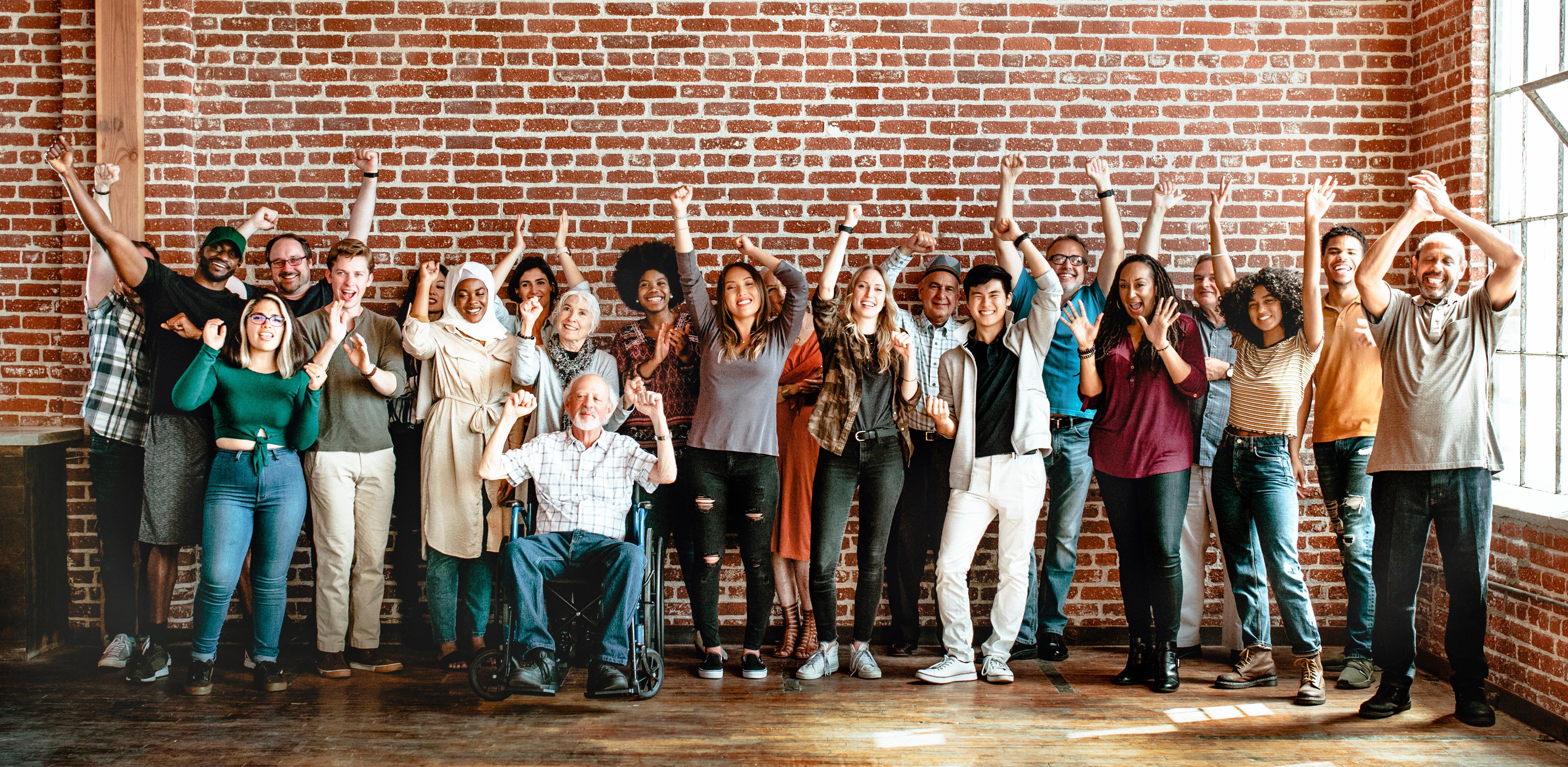 Large group of smiling people with hands raised in excitement