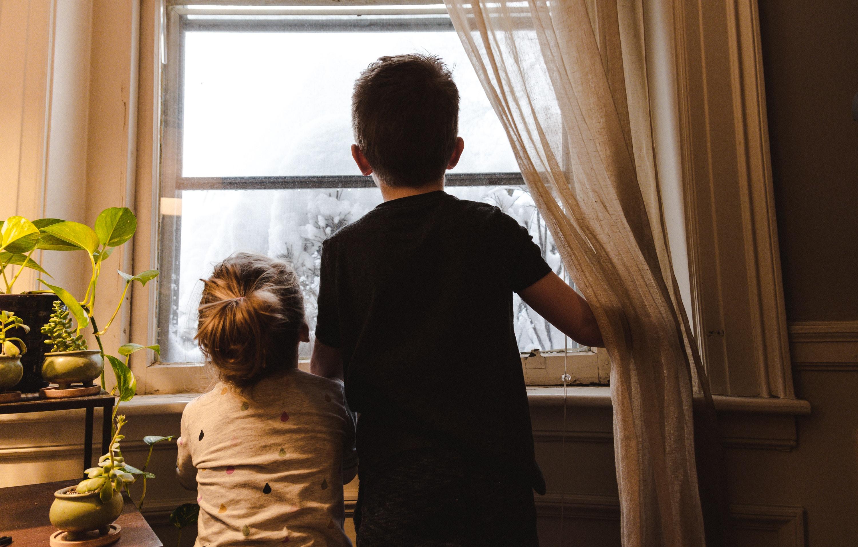 two children looking out the icy window