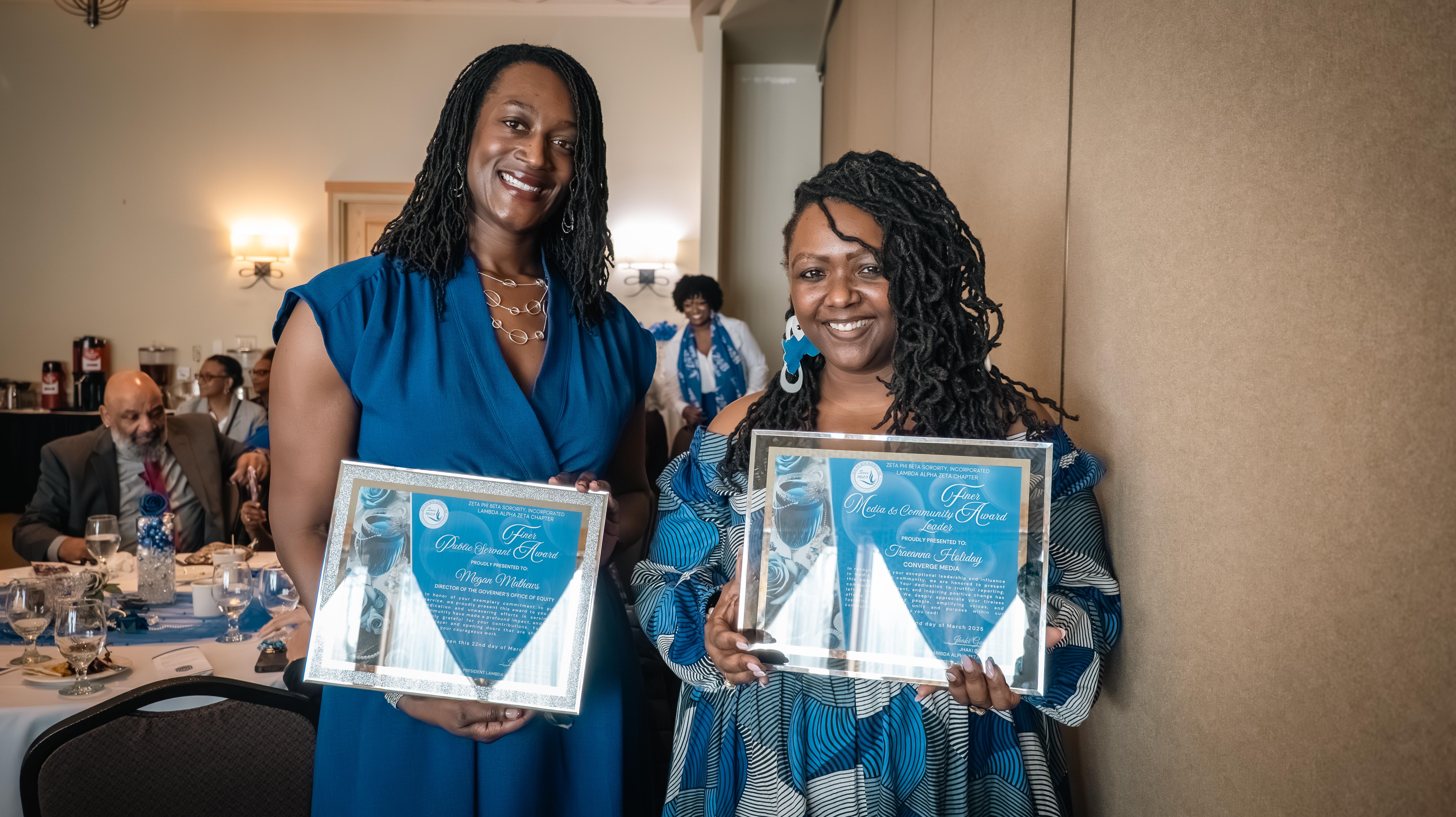 Two Black women wearing blue dresses and holding awards smile at the camera. Megan Matthews, Office of Equity Director, and TraeAnna Holiday, Office of Equity Communications Director at the Zeta Phi Beta Sorority Awards Dinner.