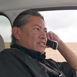 a photo of an older Native American man talking on a cellphone